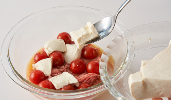 深さのある耐熱容器にAを入れてよく混ぜ合わせ、豚挽肉、ミニトマト、さらにスプーンで豆腐を大きく崩しながら加えて軽く混ぜ、ラップをして電子レンジ（500w）で3分加熱する。