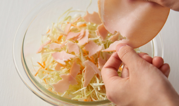 ボウルにカット野菜（キャベツ人参）を入れ、ハムを手で小さめにちぎりながら加える。